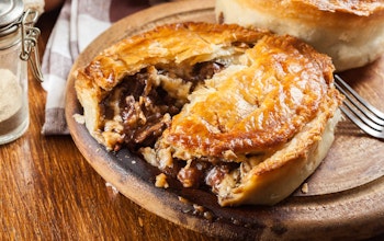 Beef & Stilton Pie  pie baked in a brown dish 1/3 cut open and revealing beef and stilton meat and gravy filling