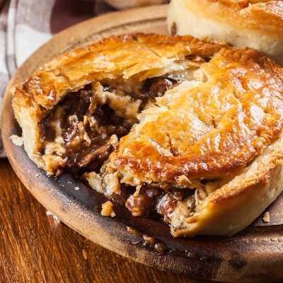 pie baked in a brown dish 1/3 cut open and revealing beef and stilton meat and gravy filling 