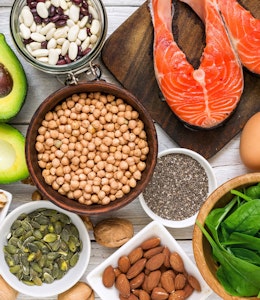 a birds eye flatlay of various nuts seeds beans and avocado spinach eggs and meat 