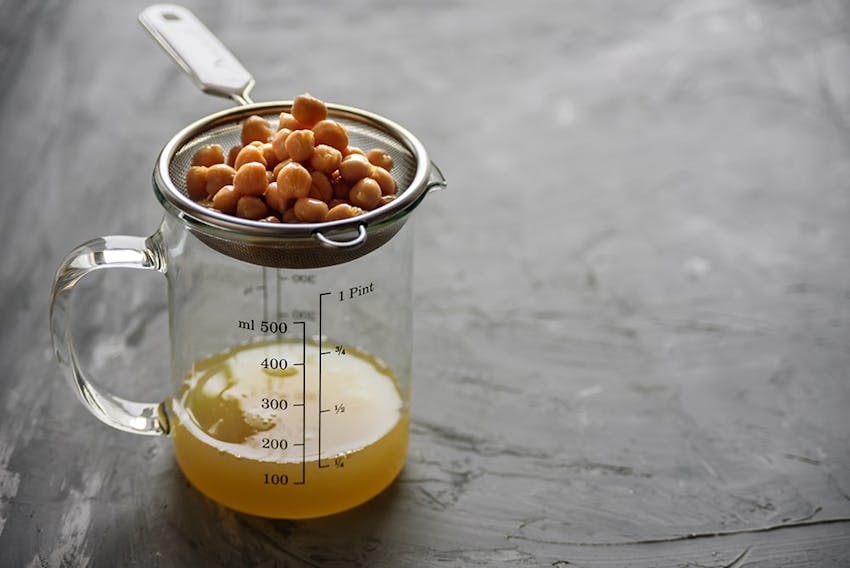 chickpeas draining over a small 500ml clear glass jug in a strainer 