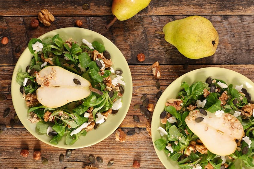 birds eye view of two plates filled with salad, pear, walnuts and cheese 