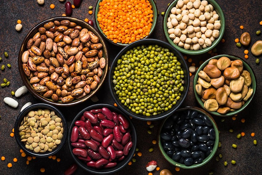 birds eye view of varying bowl sizes filled with nuts, lentils, peas and beans 