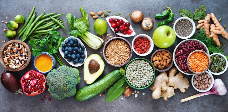 birds eye view of a large variety of rainbow coloured fruits and vegetables on top of a marble table 