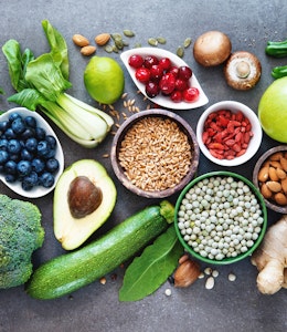 birds eye view of a large variety of rainbow coloured fruits and vegetables on top of a marble table 