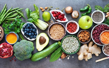 birds eye view of a large variety of rainbow coloured fruits and vegetables on top of a marble table 