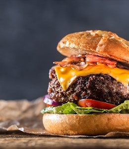 Classic Juicy Beef Burger  thick juicy beef burger with bacon lettuce tomato and american cheese in a bun topped with dressing