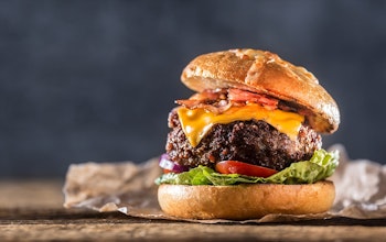 Classic Juicy Beef Burger  thick juicy beef burger with bacon lettuce tomato and american cheese in a bun topped with dressing