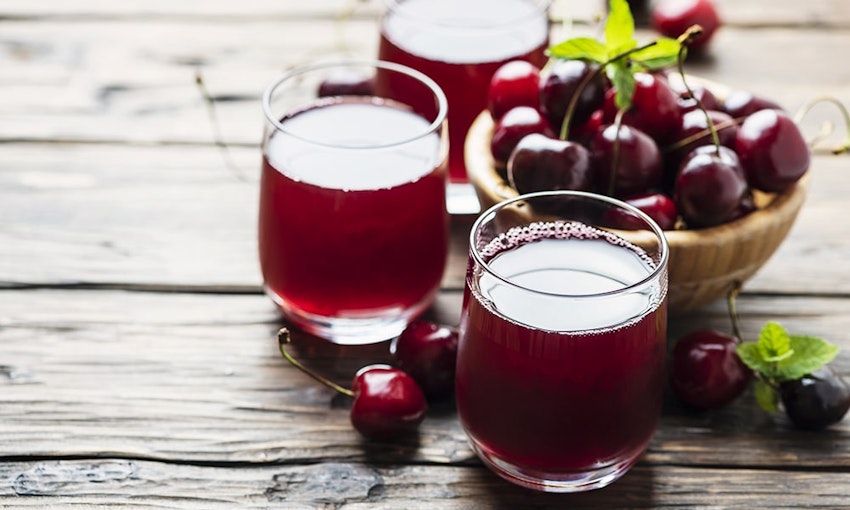 Several studies have linked cherry juice to the acceleration of muscle recovery three glasses of dark red cherry juice next to a wooden bowl of dark red cherries on top of a wooden table