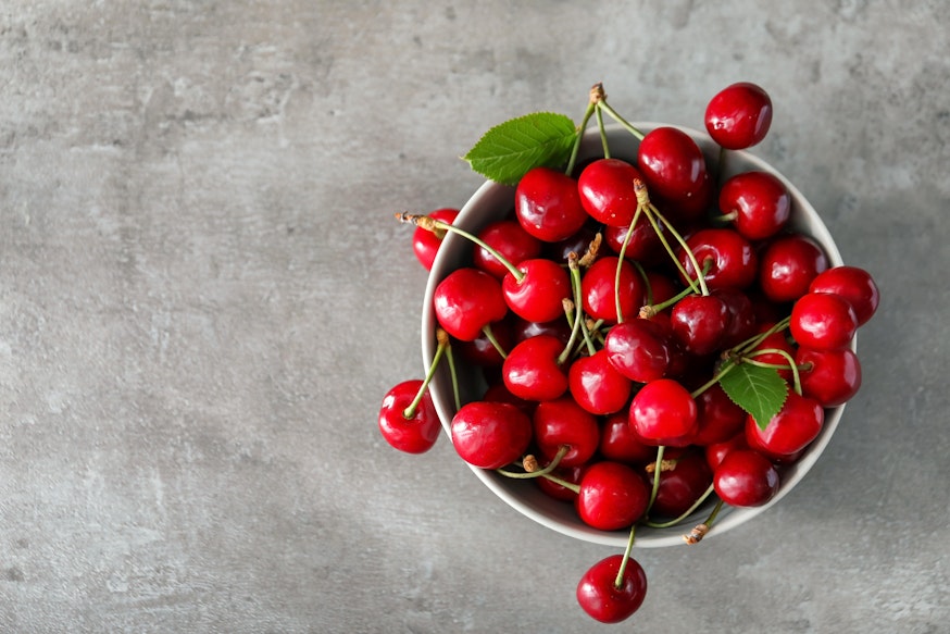 Bowl of Fresh Red Cherries birds eye view of a bowl filled with red cherries on top of a marble table