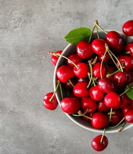 birds eye view of a bowl filled with red cherries on top of a marble table 