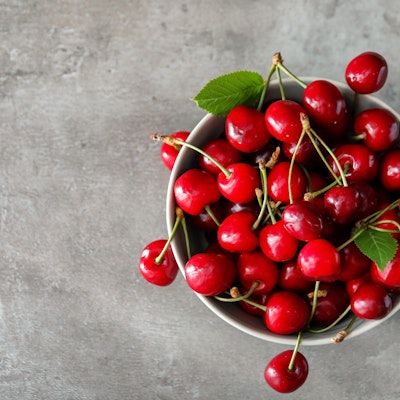 birds eye view of a bowl filled with red cherries on top of a marble table 