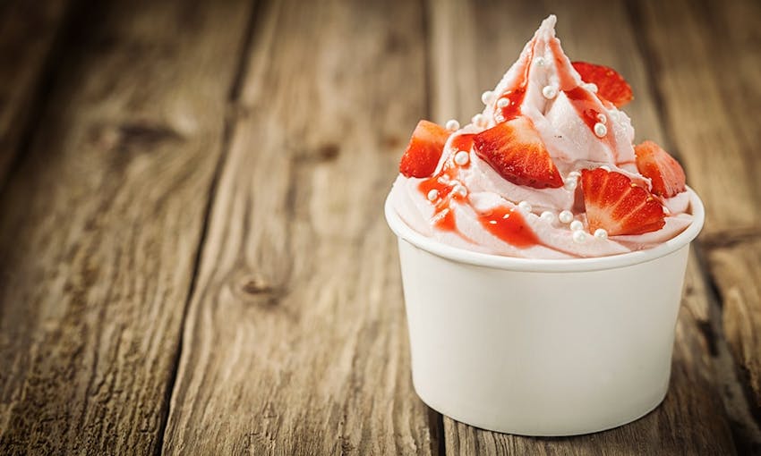 a small white tub of light and airy strawberry frozen yoghurt topped with strawberry sauce 
