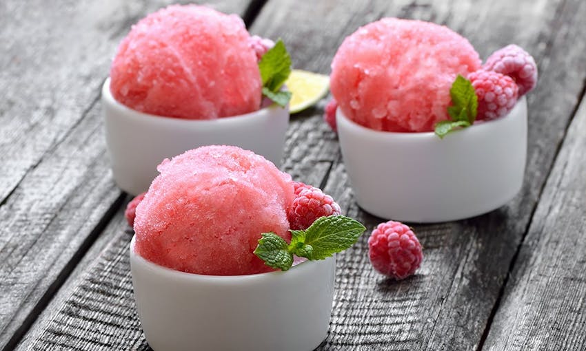 three small pots of raspberry sorbet and frozen raspberries   