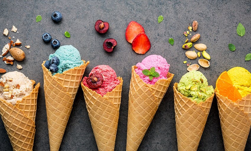 cream, blue, berry, pink, pistachio and orange flavoured ice creams in their cones decorated with fruit and nuts 