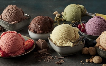 seven different colours and flavours of ice cream in stone dishes decorated with chocolate shavings and fruits 