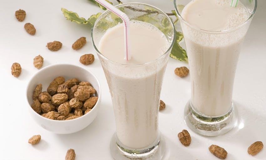 two clear glasses of tiger nut milk next to a small bowl of tiger nuts 