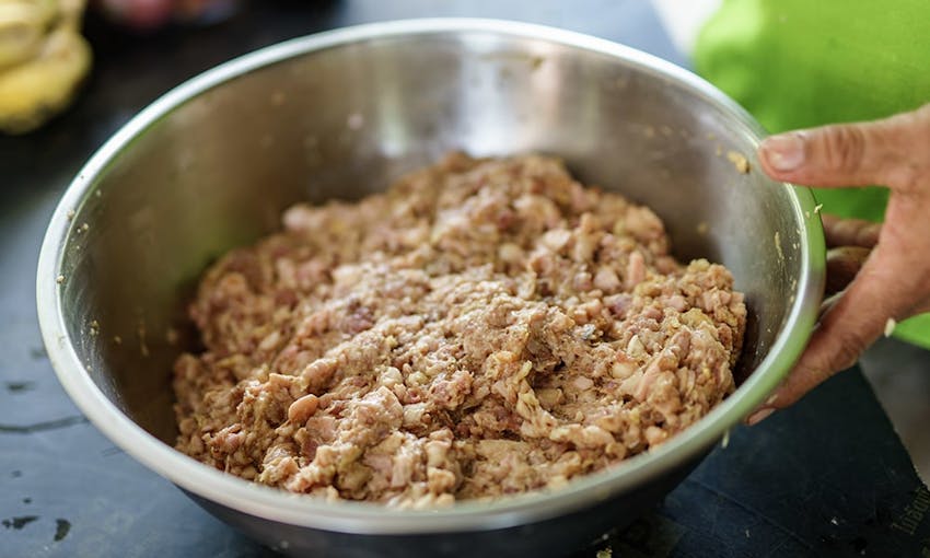 a silver bowl of sausage meat stuffing being prepared on top of kitchen countertop