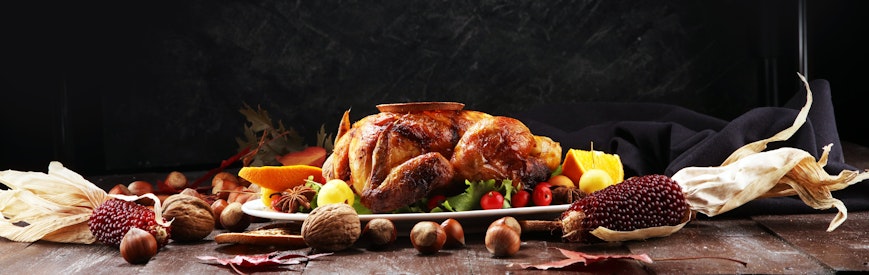 12 Meats of Christmas a table set for christmas dinner with a hot roasted turkey in the centre of a long wooden table with pine cone decorations