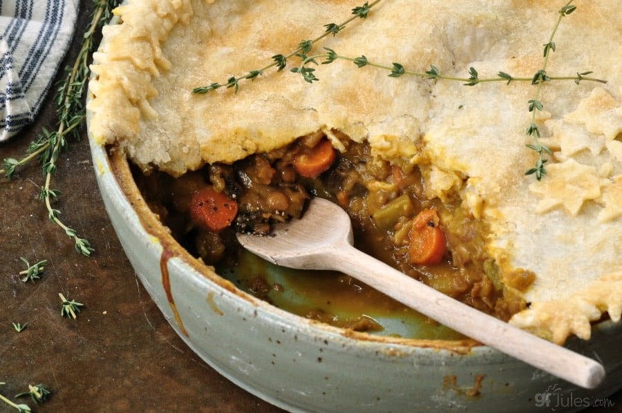 half open pie with hearty warming meat filling in a ramekin topped with a sprig of herbs