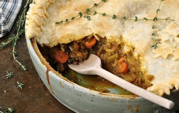 half open pie with hearty warming meat filling in a ramekin topped with a sprig of herbs