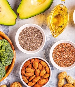 healthy dishes consisting of avocado, broccoli, seeds, nuts and vegetables on a wooden table 