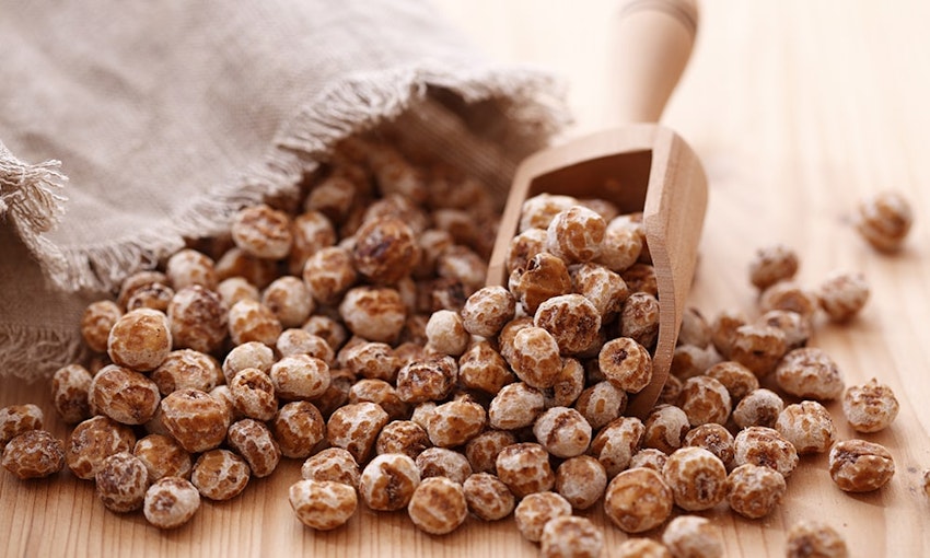 Tiger Nuts a bag of tiger nuts spilled out onto table with a small wooden rectangular scooper