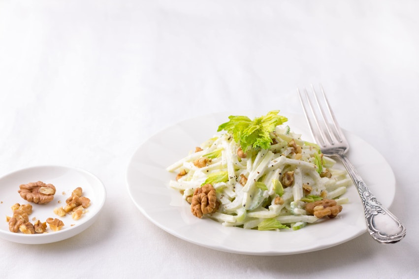 a salad consisting of celery apples walnuts grapes lettuce and mayonnaise 