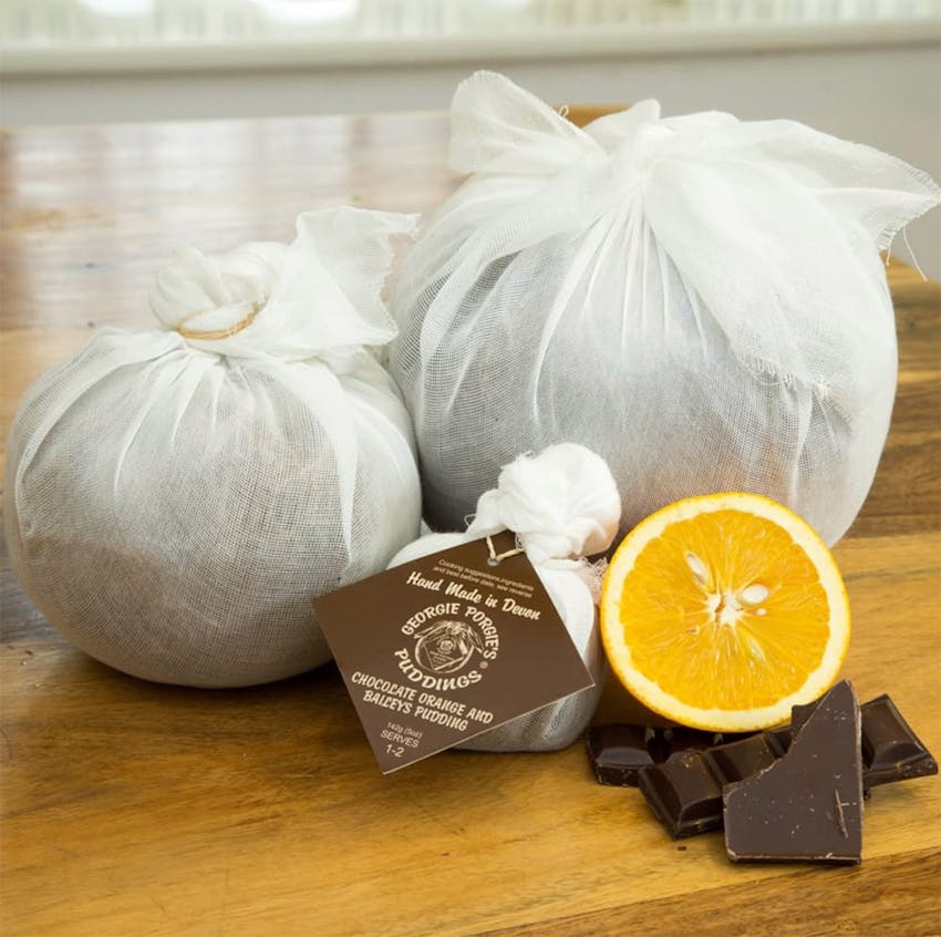 Georgie Porgie Puddings wrapped up and packaged on wooden table with dark chocolate and oranges 