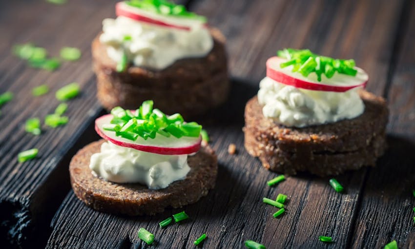 small slices of pumpernickel topped with cream cheese and radish 