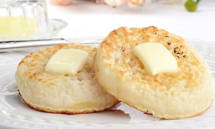 Be sure to melt butter on your crumpets! two crumpets with a knob of butter melting in the middle served on a white plate