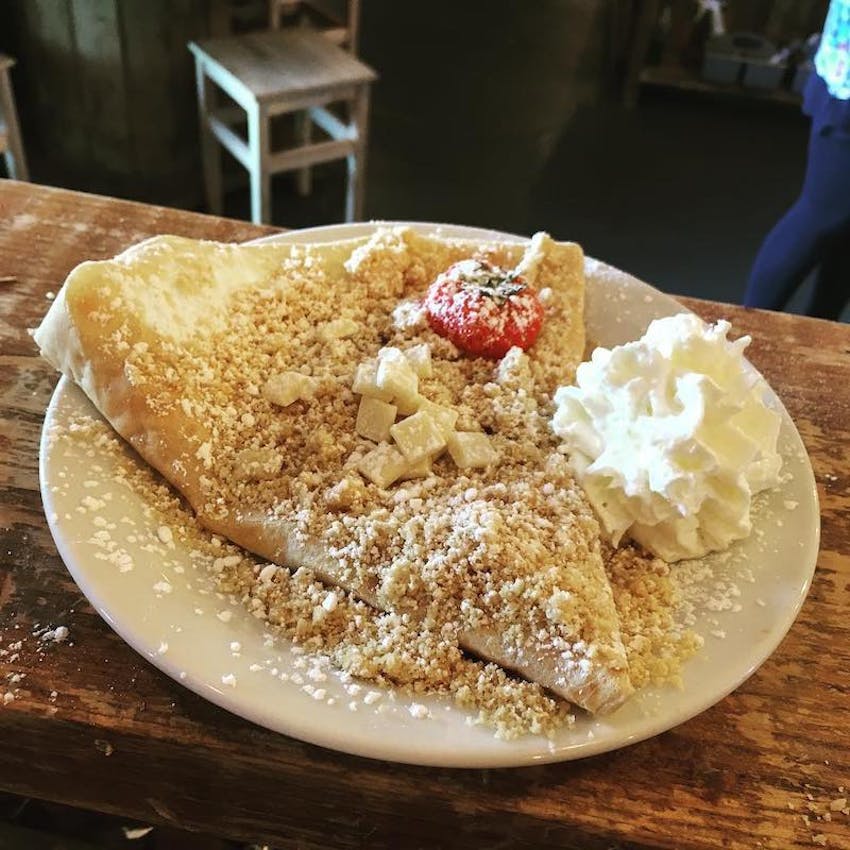 a dish of crepes topped with white chocolate, straweberries and cream at the monsieur crepe cafe in high heaton 