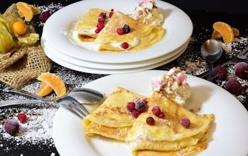 Sweet Crepes two plates of sweet crepes on a decorated table dusted with icing sugar and topped with berries