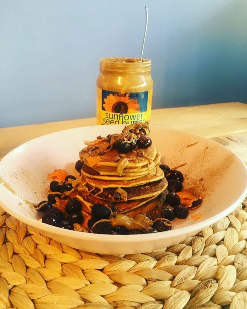 a stack of pancakes topped with sunflower seed butter and frozen berries 