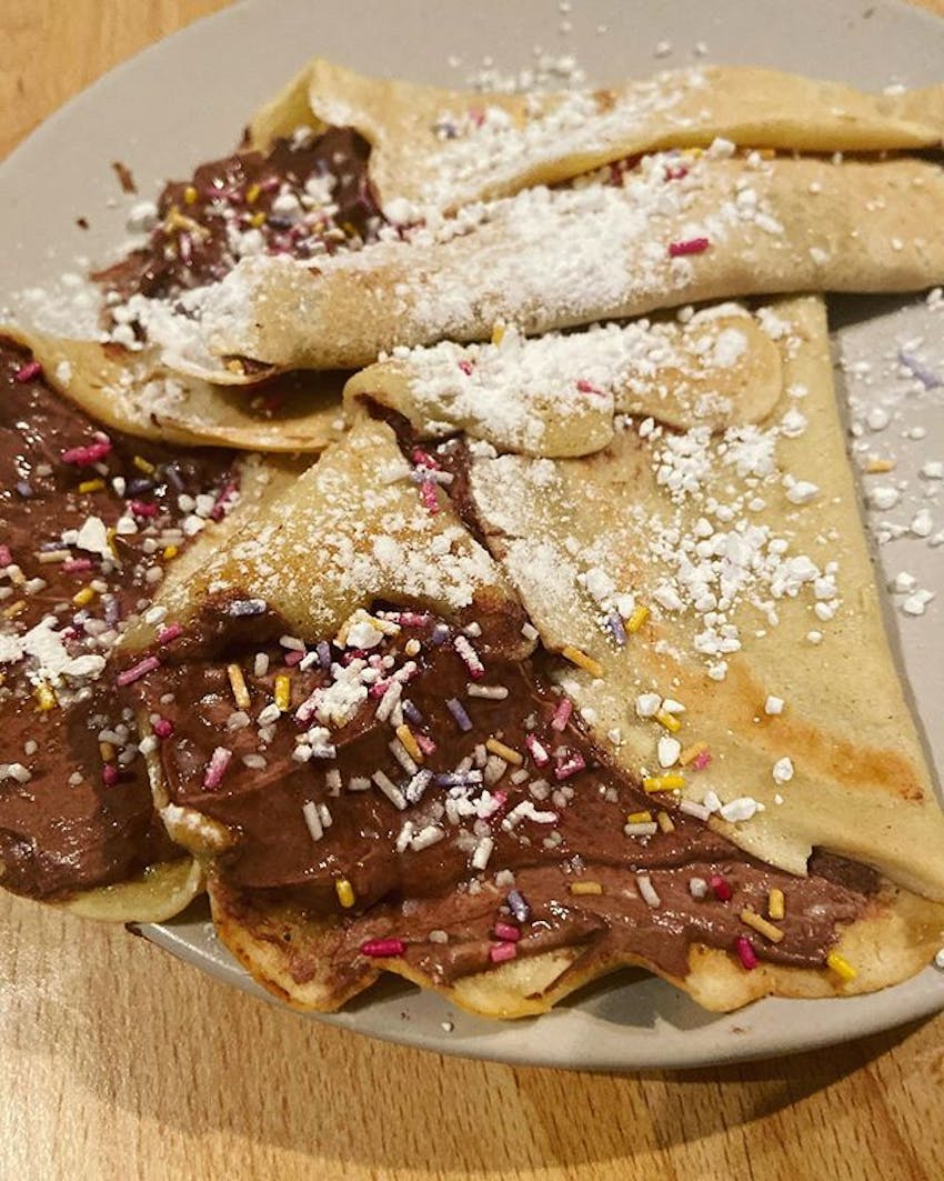 sweet crepes filled with chocolate spread and sprinkles topped with icing sugar