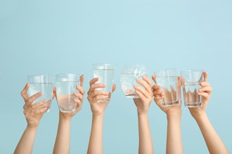 six hands holding up clear glasses of water 