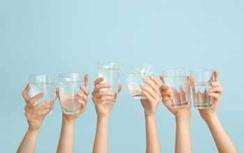 six hands holding up clear glasses of water 