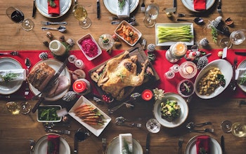 A Full Christmas Dinner  birds eye view of a fully set christmas dinner with a red table runner a turkey centre piece
