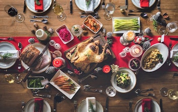 birds eye view of a fully set christmas dinner with a red table runner a turkey centre piece 