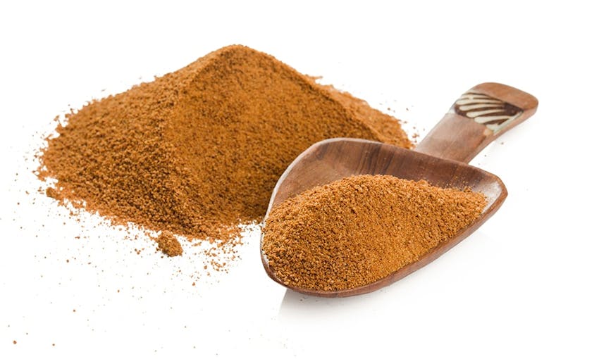 A pile of brown erythritol and a measuring spoon 