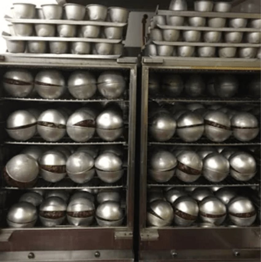 hundreds of georgie porgies christmas puddings in metal casing cooling down in the factory
