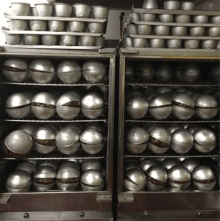 hundreds of georgie porgies christmas puddings in metal casing cooling down in the factory