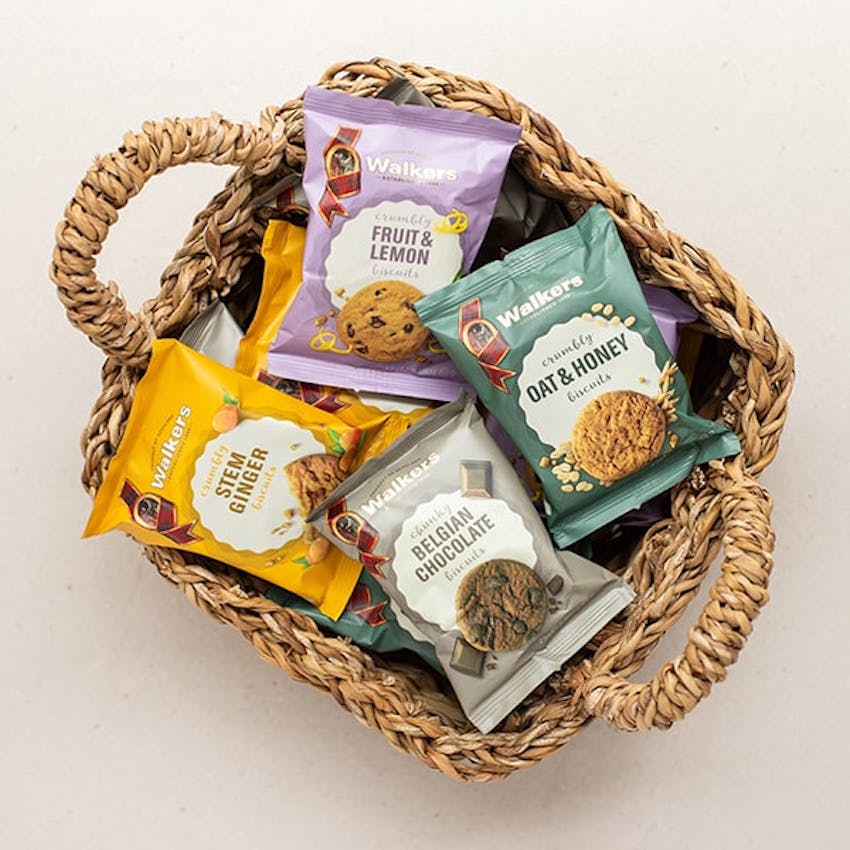 birds eye view of different coloured packets of the different flavours of walkers shortbread in a wicker basket 