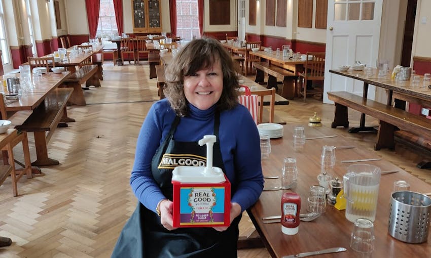 Elizabeth Jones in a large dining hall sat on a bench with a wholesale size of real good ketchup 