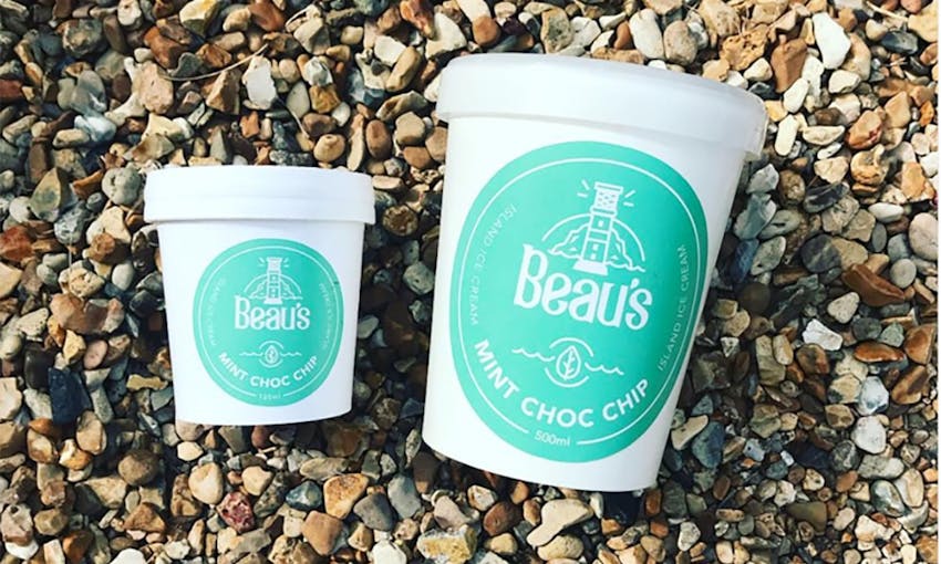 Small White and Blue Beau's Ice Cream Tub next to Large Blue and White Beau's Ice Cream Tub on Pebbled Beach 