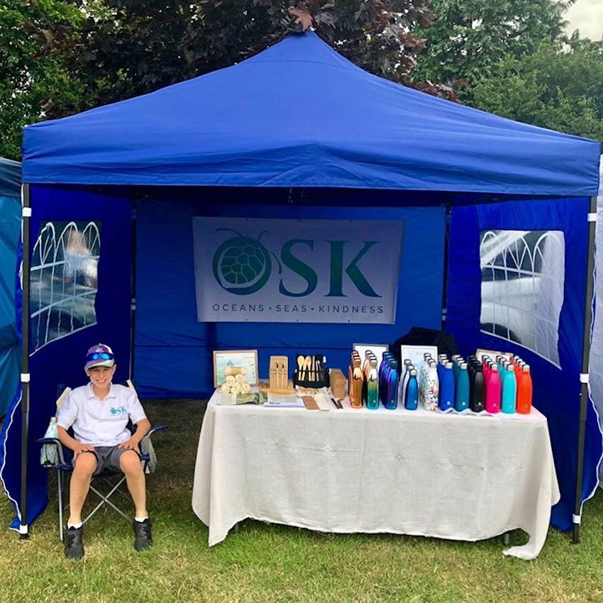 small blue gazebo with OSK logo and stall with osk merchandise manned by oskar peterson, founder of OSK