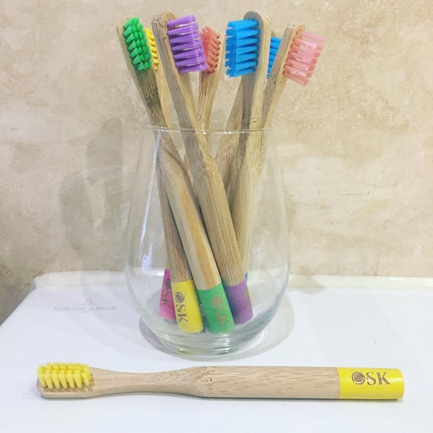glass jar of different coloured osk eco toothbrushes 