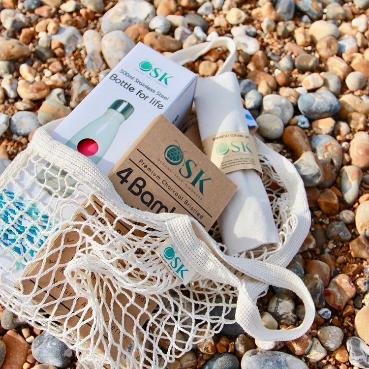 A range of OSK Eco Products sustainable osk eco bag with a range of osk eco products on a rocky beach shoreline