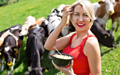 Heather Mills eating a bowl of cereal infront of a group of cows 