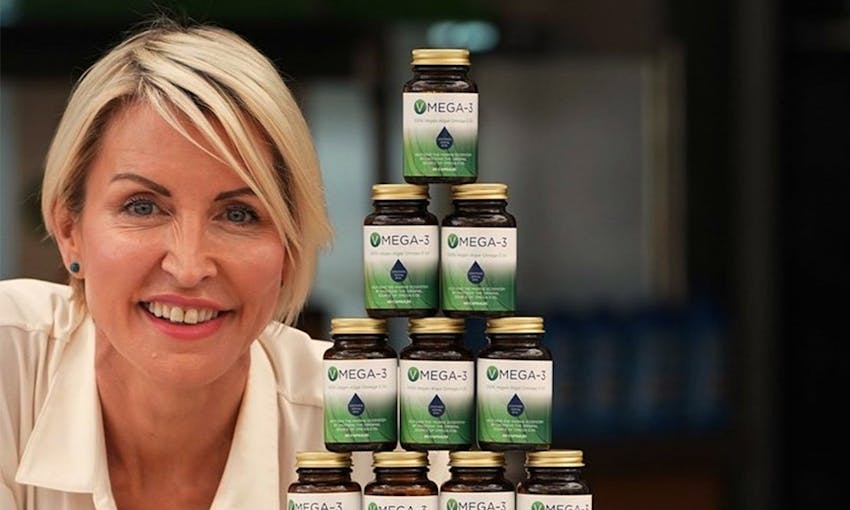 Heather mills smiling next to a stacked pyramid of Vmega 3 Algal Oil 