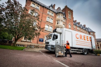 Creed Lorry in front of red brick building with tree